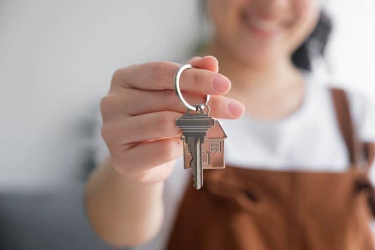 A closeup photo of a woman's hand with a key to her new house