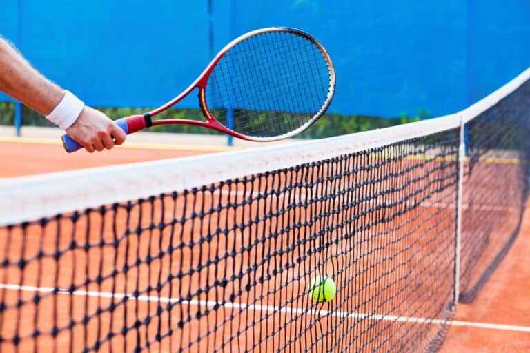 Cropped image of a tennis racket, net, and ball in the concept of services and amenities in Wimbledon.